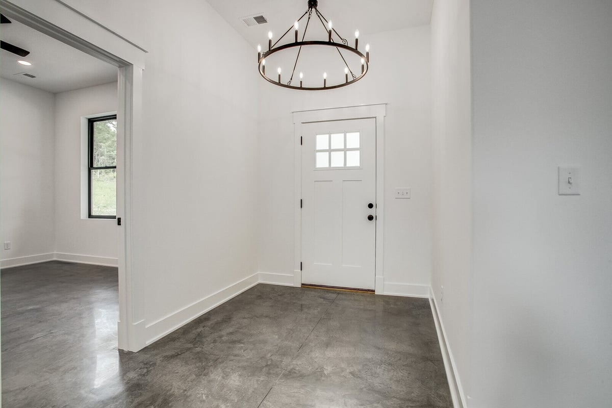 Contemporary home entryway featuring a white front door and a black chandelier