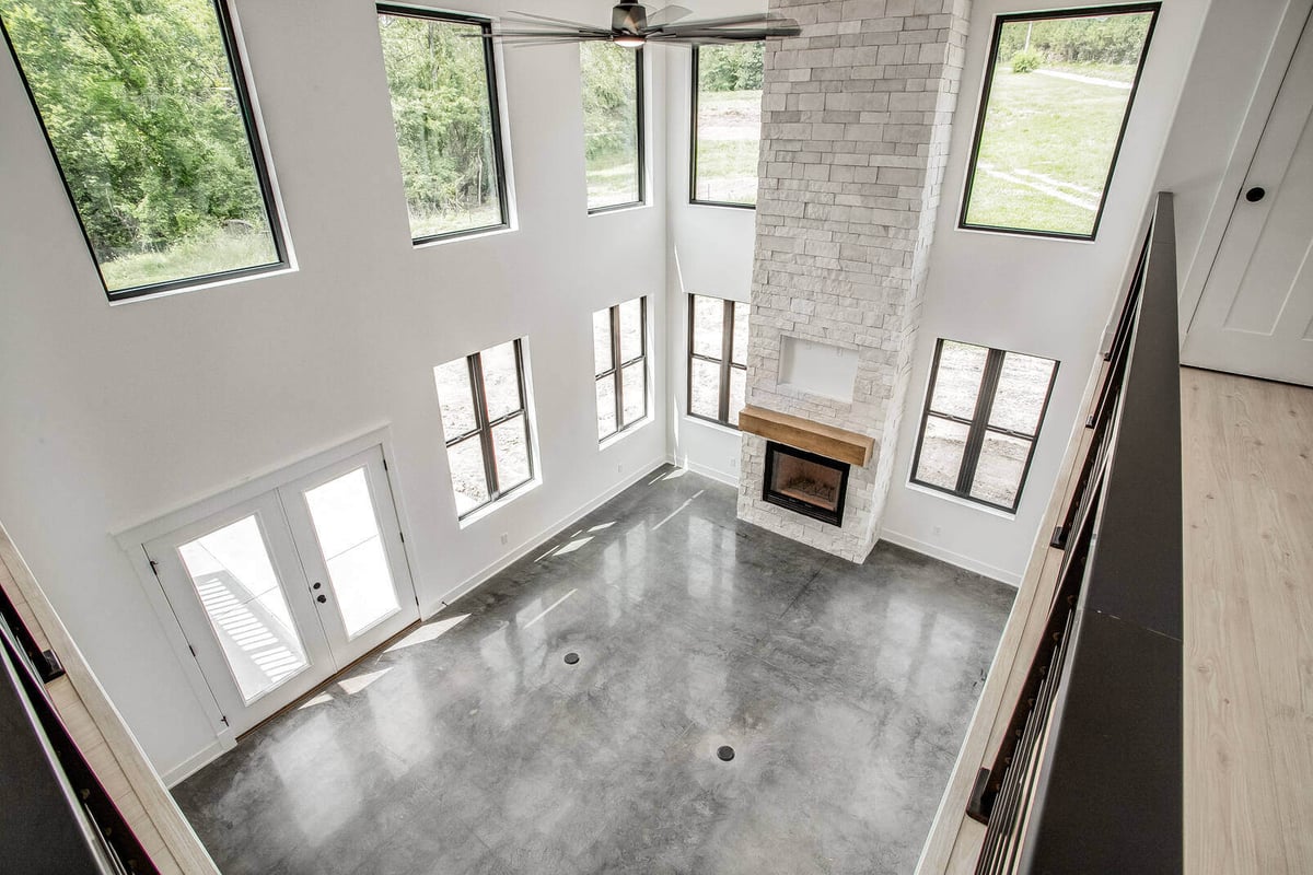 Double-height living room with a floor-to-ceiling stone fireplace and large windows