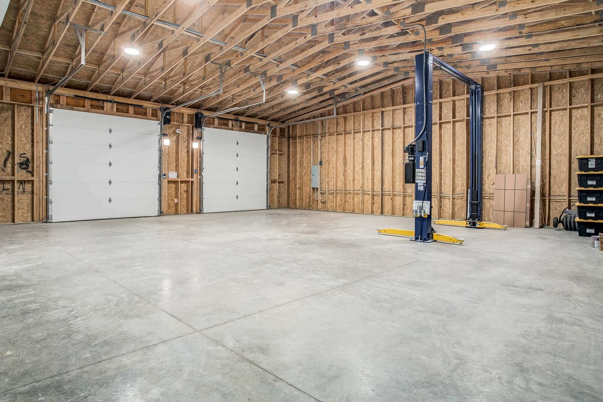 Expansive garage workshop with exposed wood beams, concrete floors, and a car lift, part of a Metro Kansas City home remodel by Top Shelf Home Builders.jpg