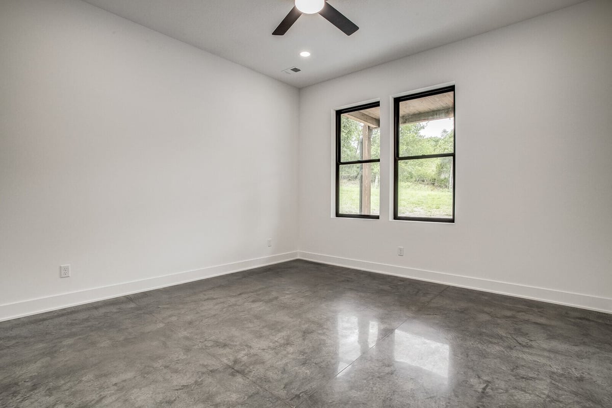 Spacious bedroom with polished concrete floors and modern black-framed windows