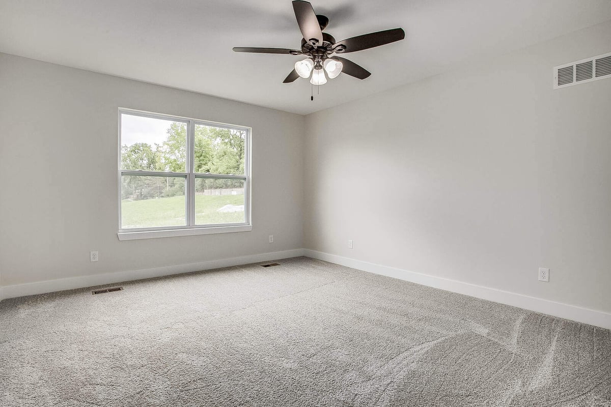 Bright bedroom with a ceiling fan, plush carpet, and large windows in Burton home remodel